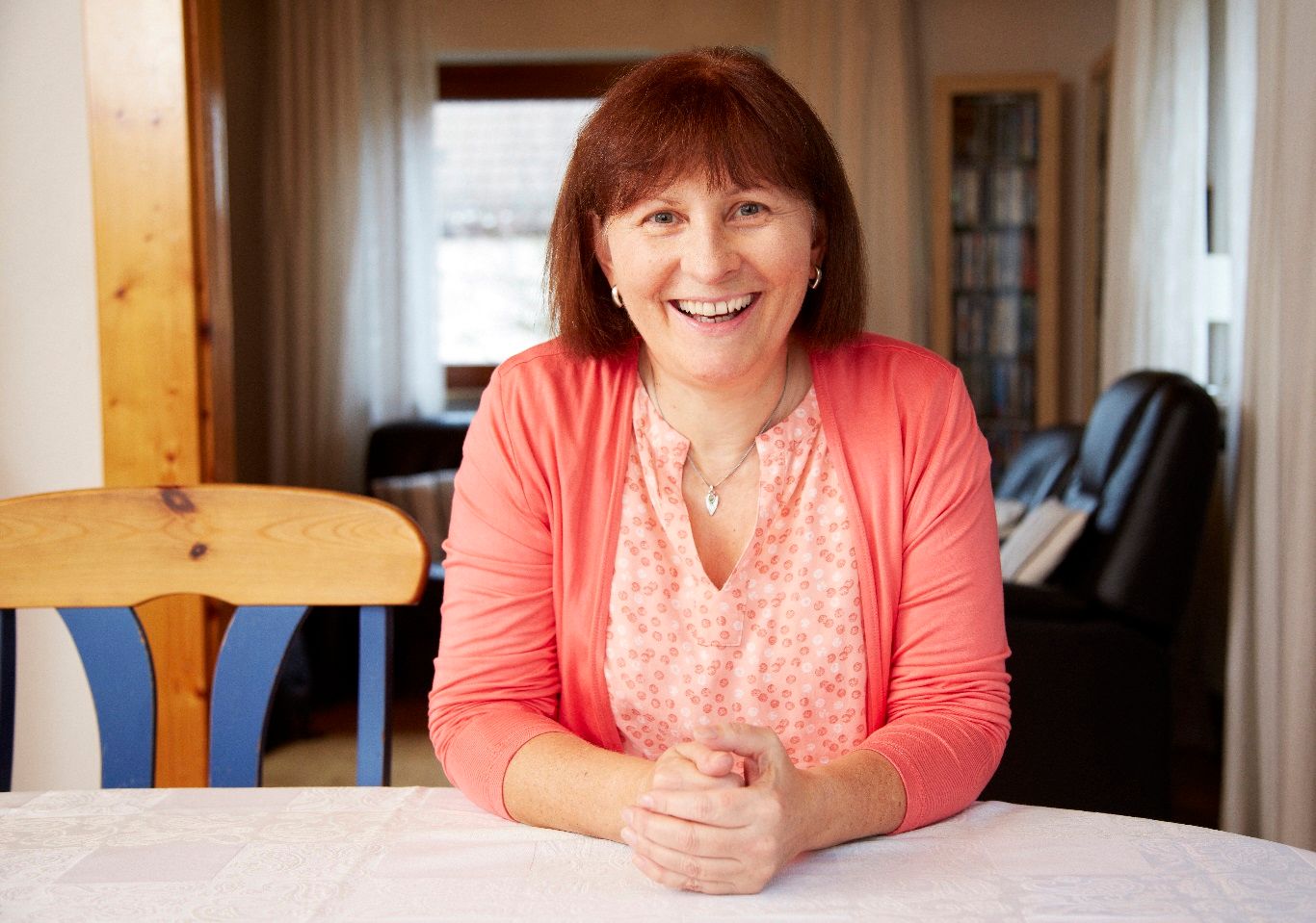 Porträt von Helga Kröner-Schock 2017, die lächelnd an einem Tisch sitzt.