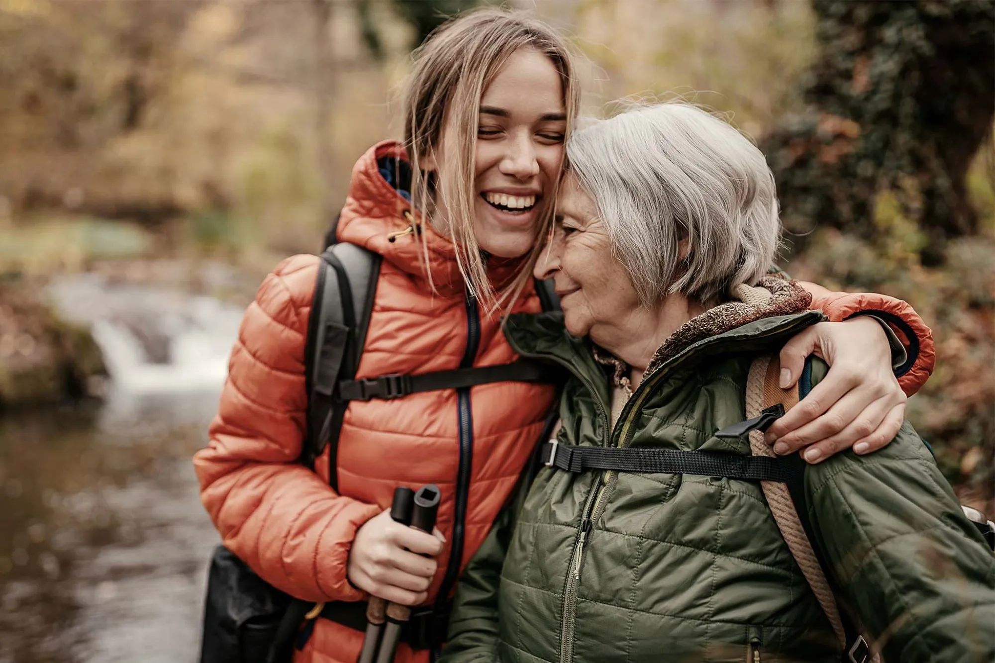 Eine junge Frau umarmt eine ältere Frau beim Wandern in der Natur