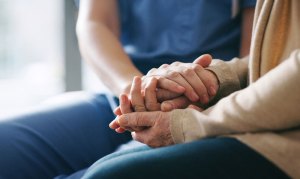 Darmkrebs: Eine Pflegerin hält die Hand einer Patientin.