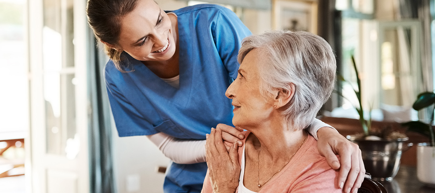 Immuntherapie bei Krebs: Lächelnde Patientin mittleren Alters und Krankenschwester im blauen Kittel.