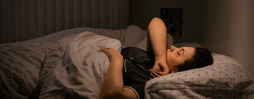 Chronischer Husten: Eine hustende Frau liegt im Bett.