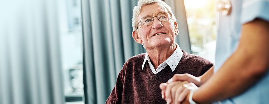 Älterer Patient hält die Hand des Arztes.