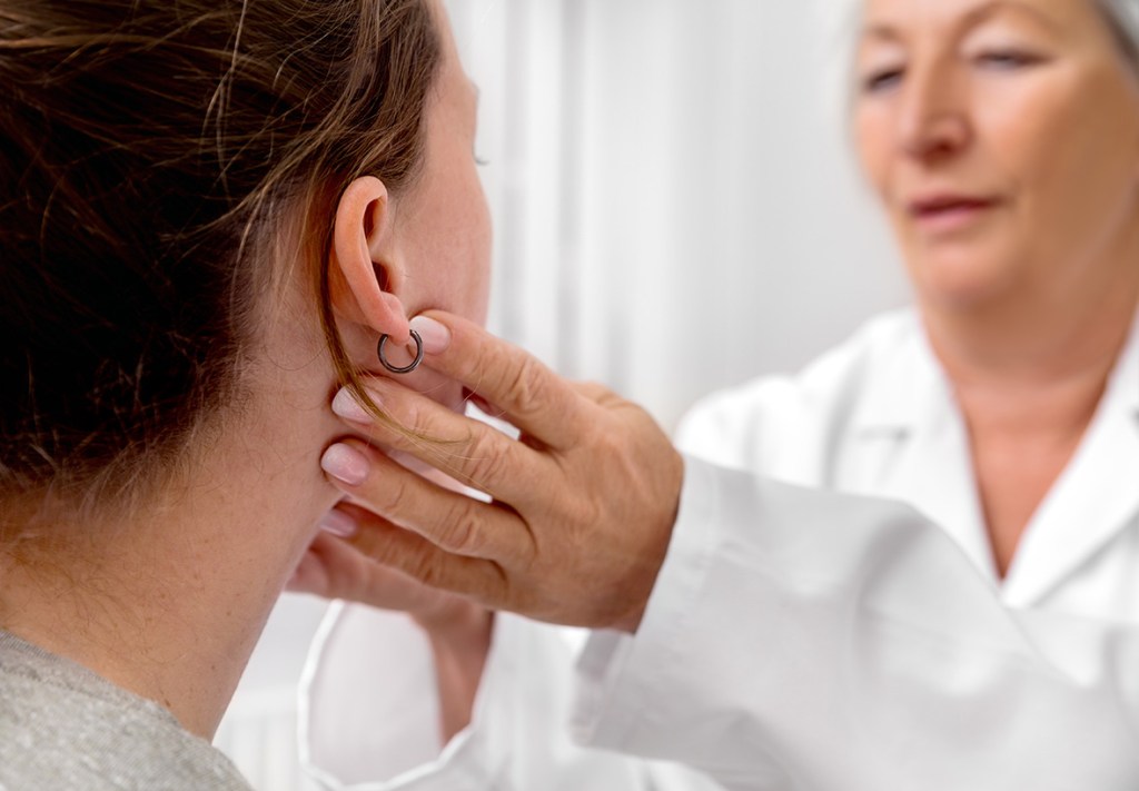 Eine Ärztin tastet die Lymphknoten am Hals einer Patientin ab.