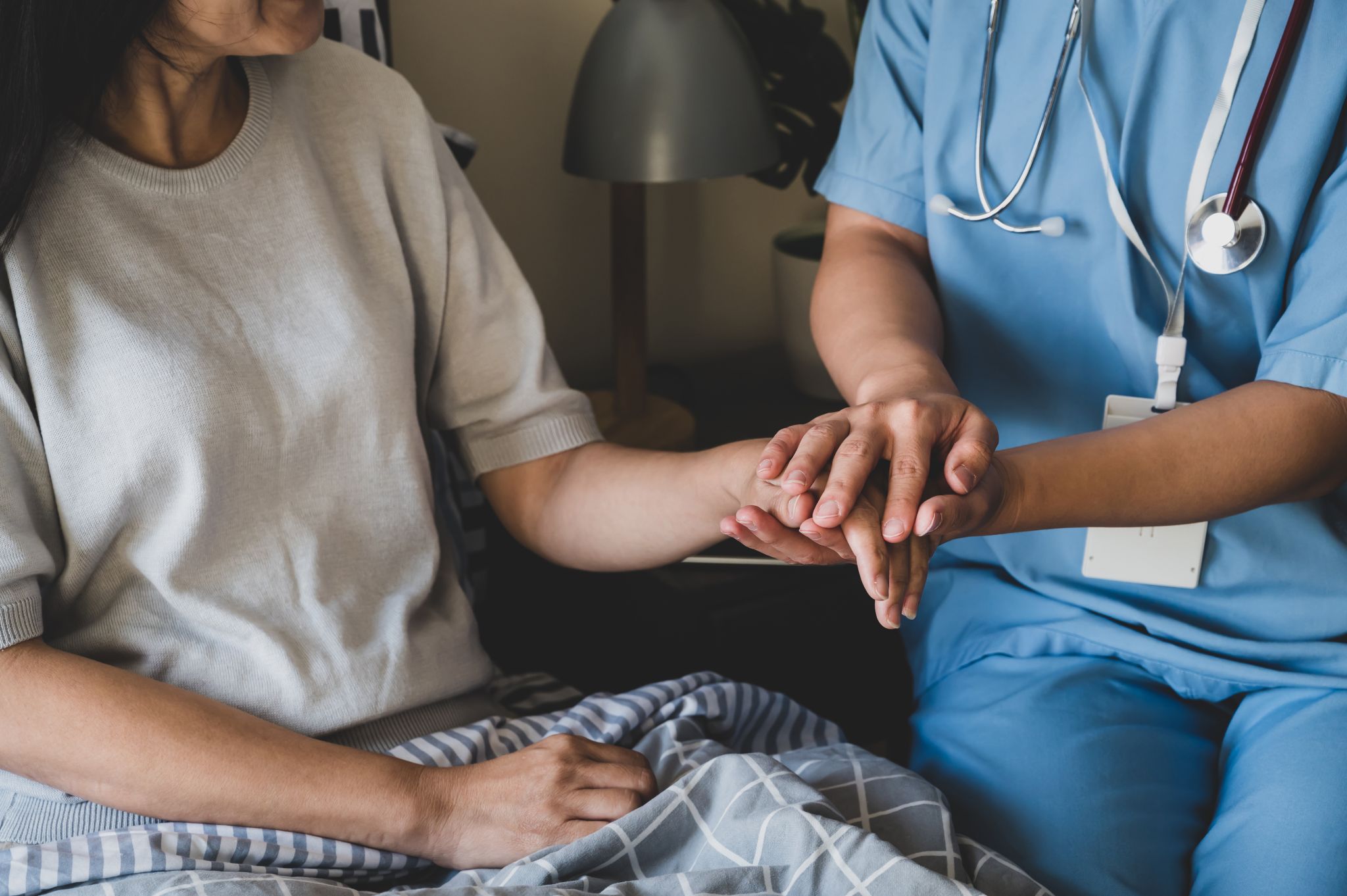 Nahaufnahme zeigt die Hände einer Pflegekraft, die die Hand einer Patientin hält.