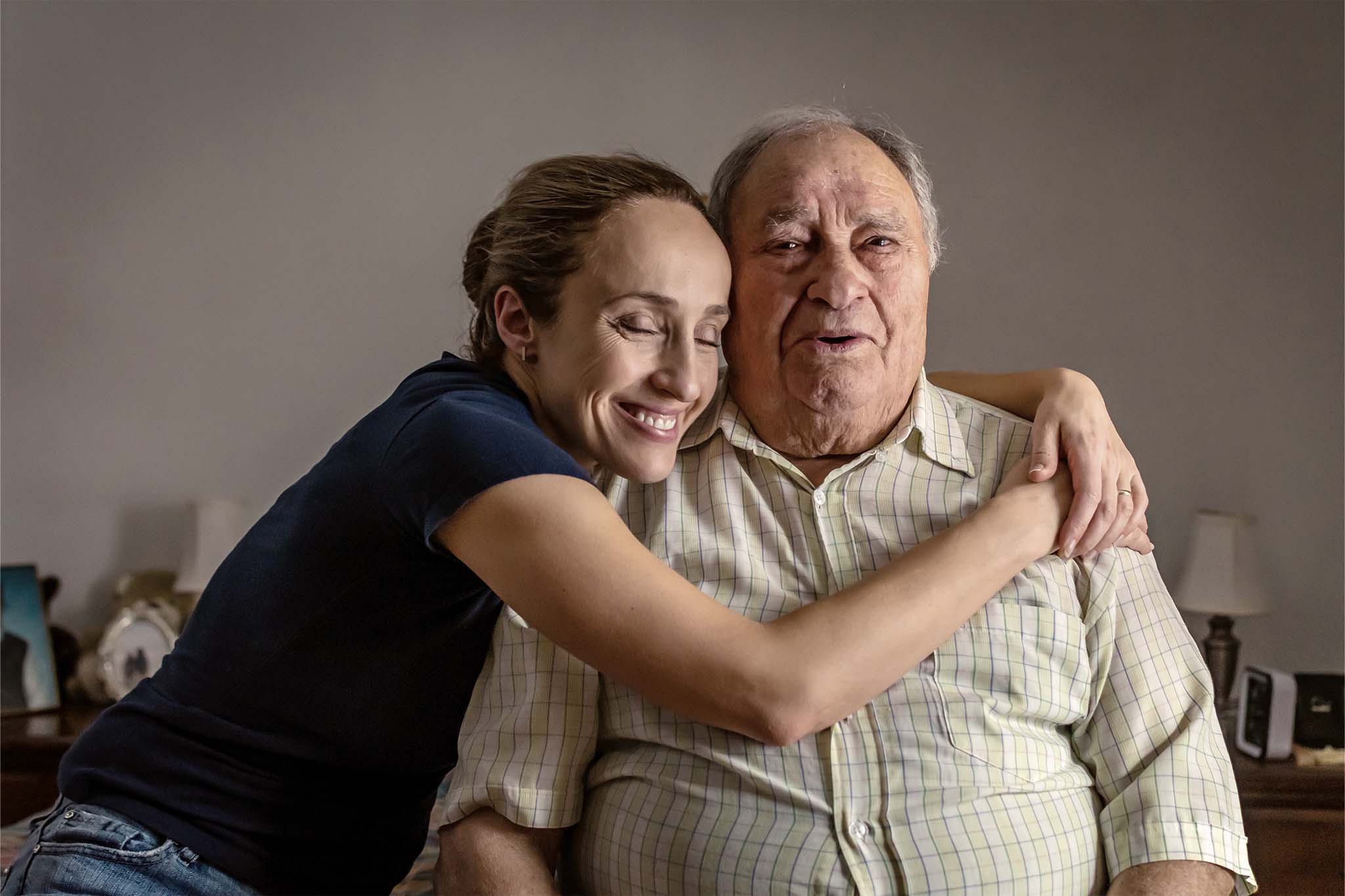 Eine junge Frau umarmt ihren Großvater.