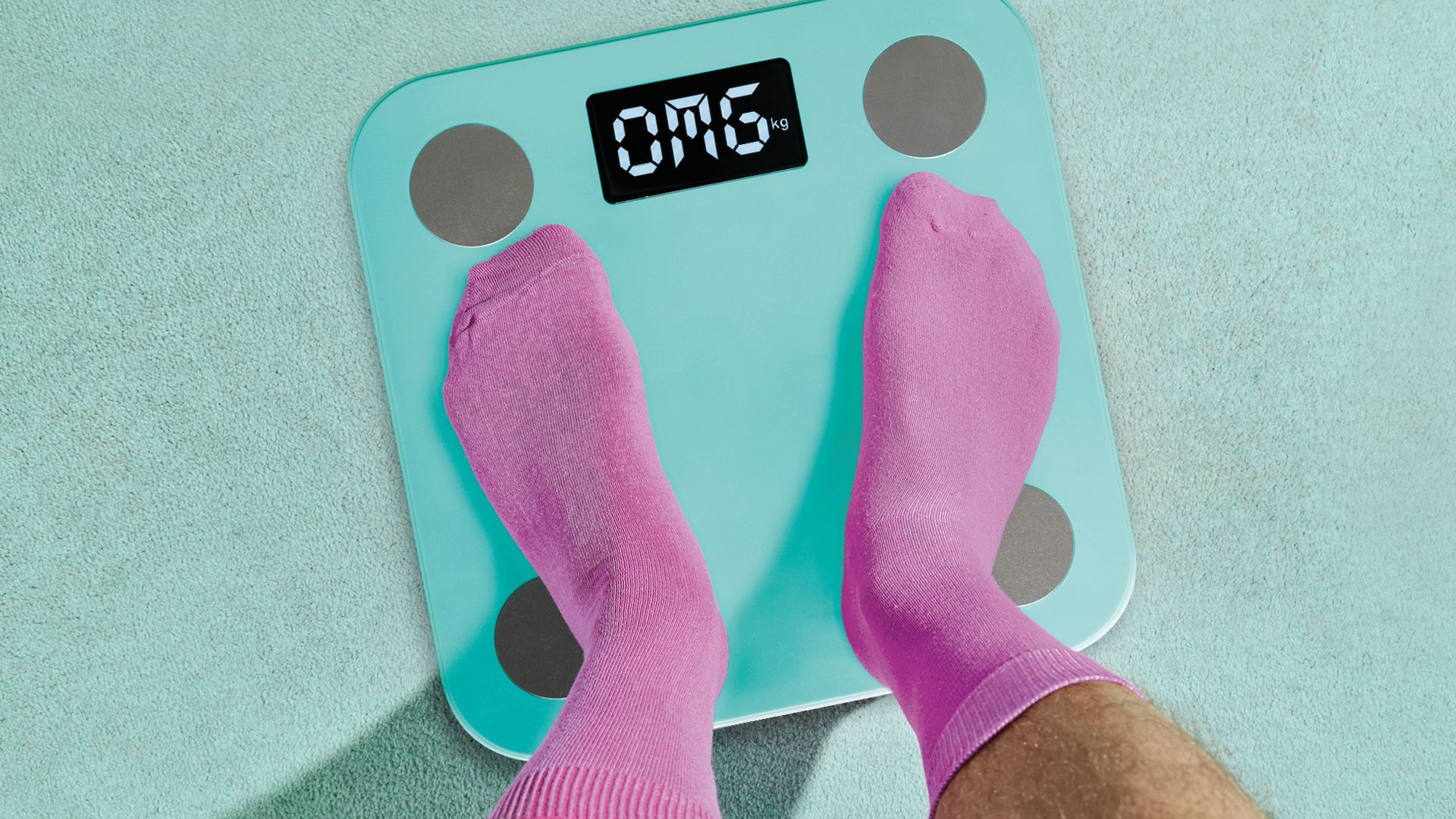 Zwei Füße in rosa Socken stehen auf einer Waage mit der Aufschrift OMG.