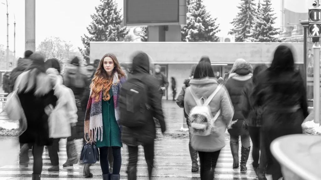 Rückenansicht von schwarz-weißer Menschengruppe und bunte Frau nach vorn im Fokus