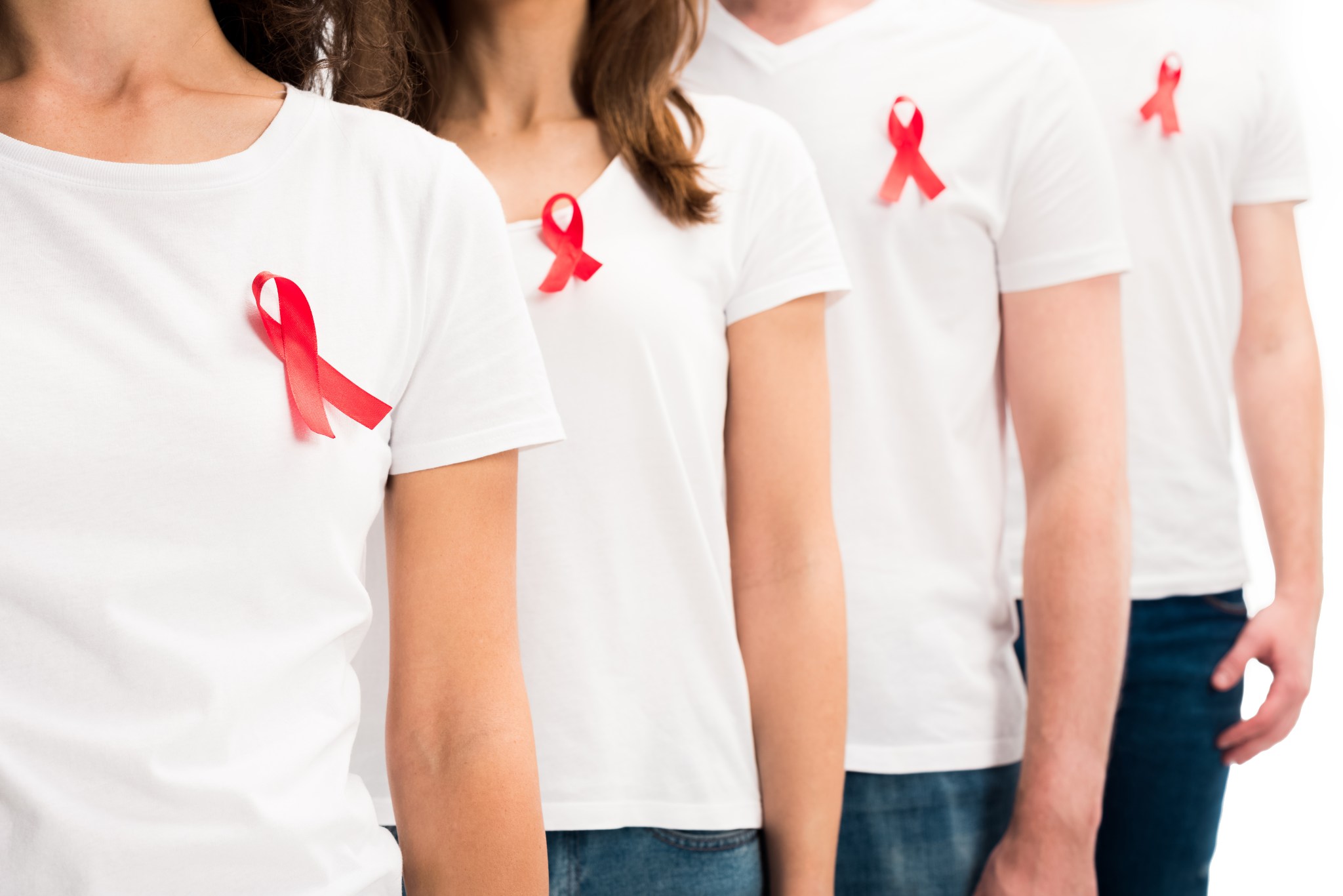 Oberkörper von 4 Personen, die weiße T-Shirts tragen und die rote Aids-Schleife 