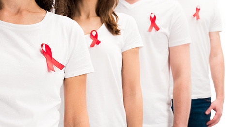 Mehrere Menschen tragen eine rote Schleife an ihrem T-Shirt.