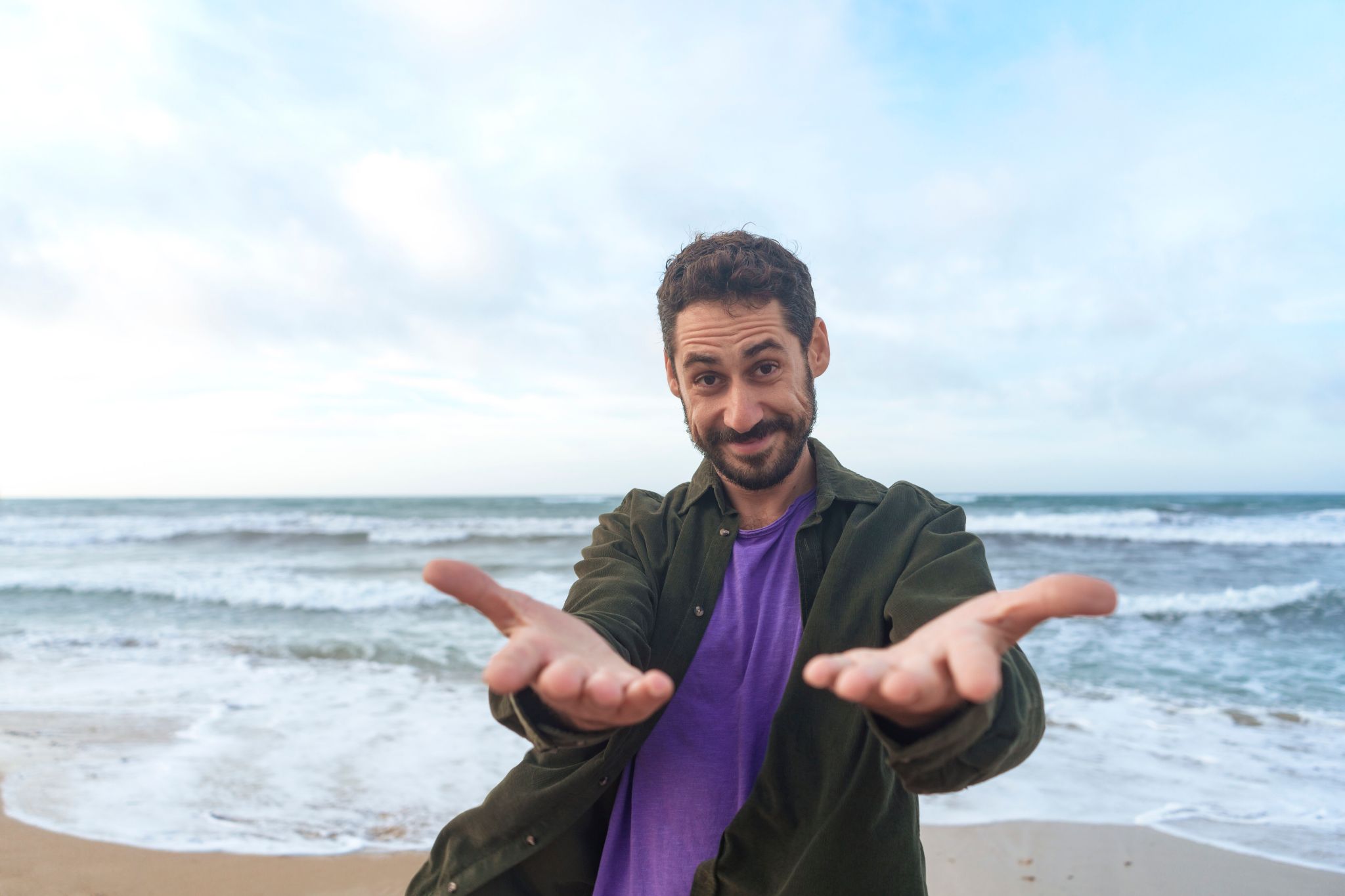 Ein Mann steht am Strand und zeigt mit den Händen auf dich