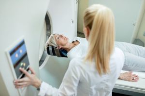 Eine Patientin liegt für eine Untersuchung auf dem Untersuchungstisch. Eine medizinische Fachkraft bedient das Gerät und bereitet die Untersuchung vor.