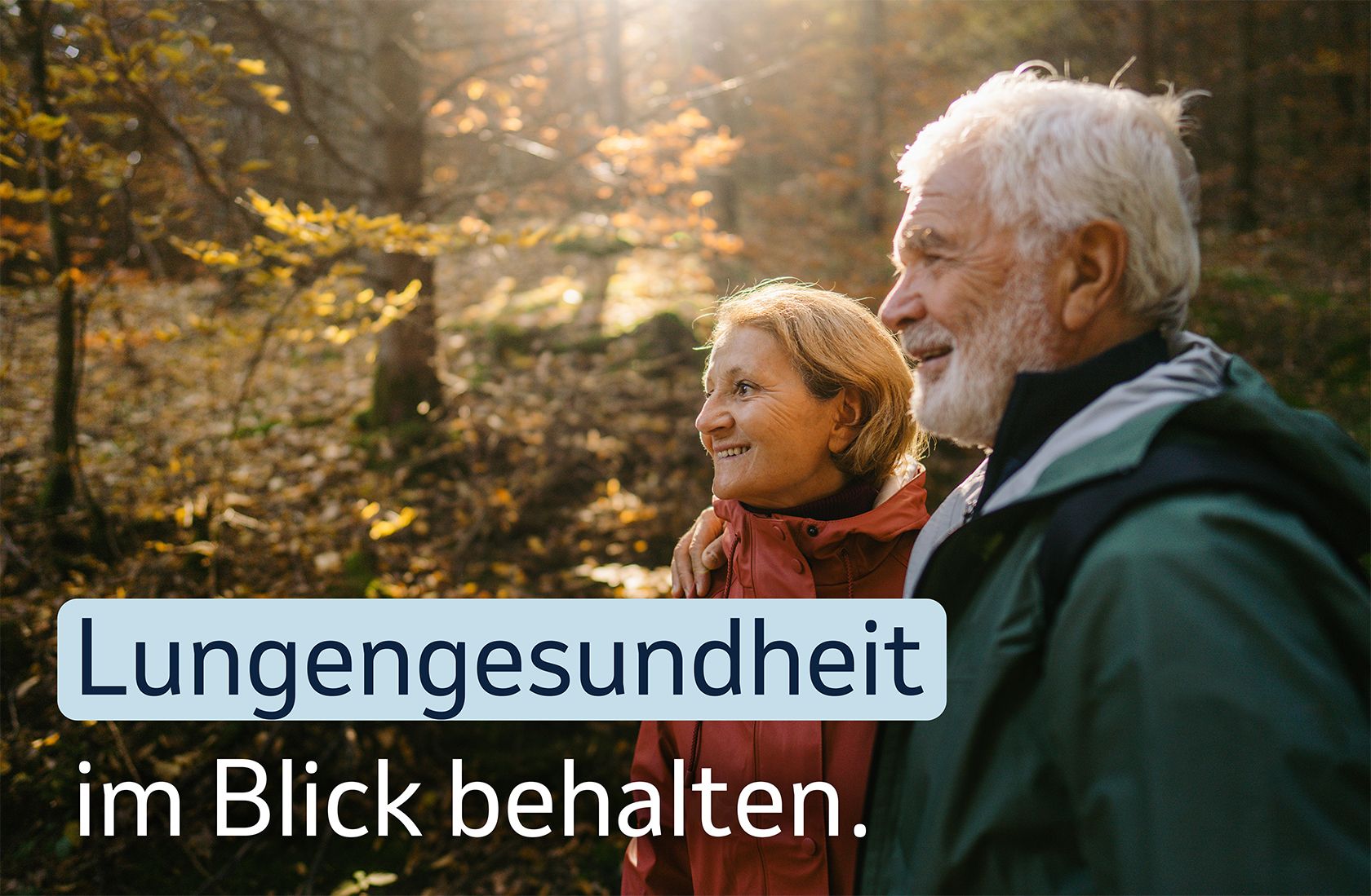 Ein älteres Paar spaziert lächelnd im Herbstwald, mit dem Text „ Lungengesundheit im Blick behalten.“