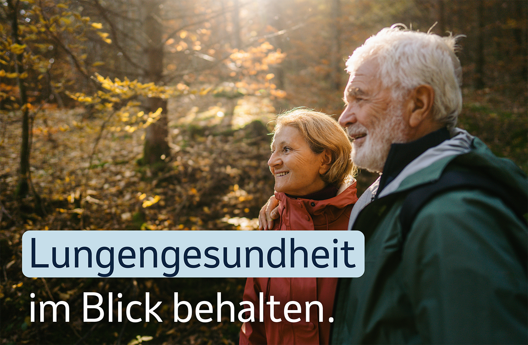 Ein älteres Paar spaziert lächelnd im Herbstwald, mit dem Text „ Lungengesundheit im Blick behalten.“