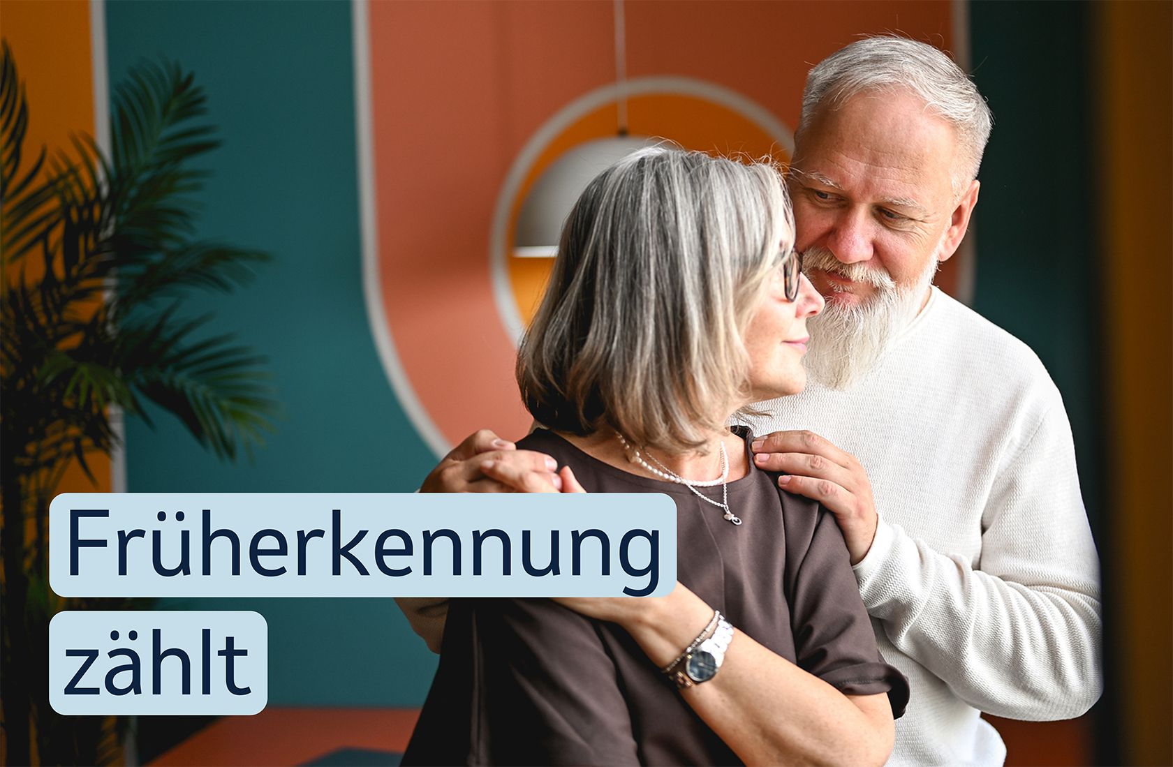 EIN älteres Paar umarmt sich. Auf dem Bild steht der Text „Früherkennung zählt“.